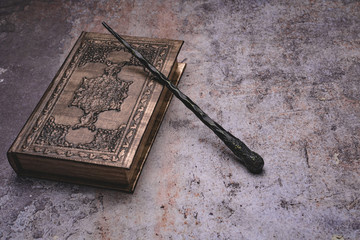 Old book with spells and magic wand on gray background. Copy space for text