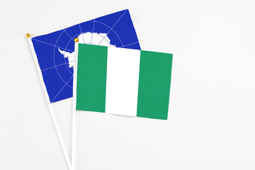 Nigeria and Antarctica stick flags on white background. High quality fabric, miniature national flag. Peaceful global concept.White floor for copy space.