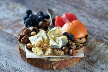 Selective focus. Beautiful cheese set with nuts, blue grapes and grape fruit. Keto snack. Healthy...