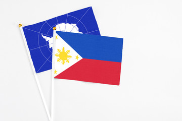 Philippines and Antarctica stick flags on white background. High quality fabric, miniature national flag. Peaceful global concept.White floor for copy space.