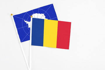 Romania and Antarctica stick flags on white background. High quality fabric, miniature national flag. Peaceful global concept.White floor for copy space.