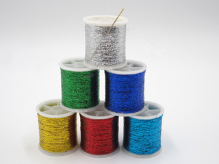 Bobinas de hilos metalizados en distintos colores y una aguja