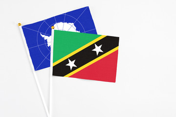 Saint Kitts And Nevis and Antarctica stick flags on white background. High quality fabric, miniature national flag. Peaceful global concept.White floor for copy space.