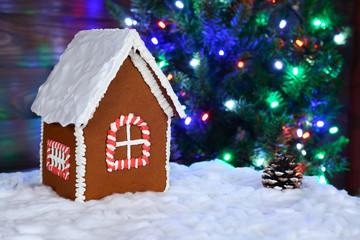 The hand-made eatable gingerbread house, snow decoration, New Year Tree with garland in background