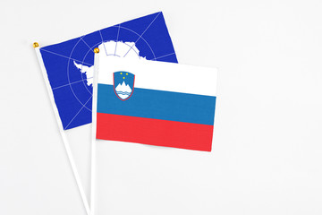 Slovenia and Antarctica stick flags on white background. High quality fabric, miniature national flag. Peaceful global concept.White floor for copy space.