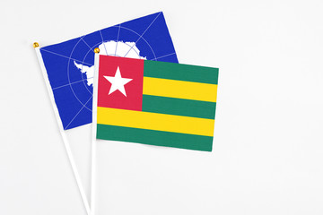 Togo and Antarctica stick flags on white background. High quality fabric, miniature national flag. Peaceful global concept.White floor for copy space.