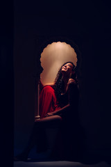 Muslim female sitting on a decorated moroccan window at a hotel resort. Travel around the world....