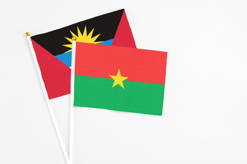 Burkina Faso and Antigua and Barbuda stick flags on white background. High quality fabric, miniature national flag. Peaceful global concept.White floor for copy space.