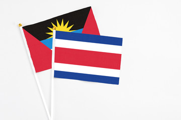 Costa Rica and Antigua and Barbuda stick flags on white background. High quality fabric, miniature national flag. Peaceful global concept.White floor for copy space.