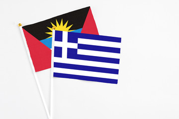 Greece and Antigua and Barbuda stick flags on white background. High quality fabric, miniature national flag. Peaceful global concept.White floor for copy space.