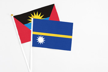 Nauru and Antigua and Barbuda stick flags on white background. High quality fabric, miniature national flag. Peaceful global concept.White floor for copy space.