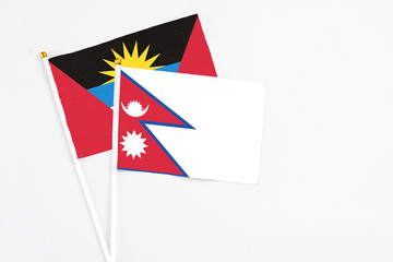 Nepal and Antigua and Barbuda stick flags on white background. High quality fabric, miniature national flag. Peaceful global concept.White floor for copy space.
