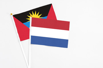 Netherlands and Antigua and Barbuda stick flags on white background. High quality fabric, miniature national flag. Peaceful global concept.White floor for copy space.