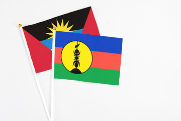 New Caledonia and Antigua and Barbuda stick flags on white background. High quality fabric, miniature national flag. Peaceful global concept.White floor for copy space.