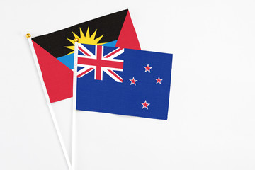 Fototapeta premium New Zealand and Antigua and Barbuda stick flags on white background. High quality fabric, miniature national flag. Peaceful global concept.White floor for copy space.