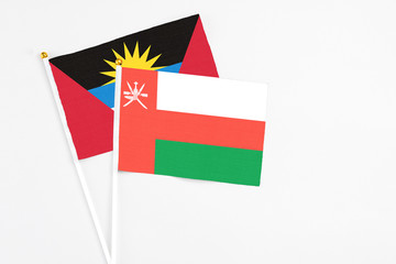 Oman and Antigua and Barbuda stick flags on white background. High quality fabric, miniature national flag. Peaceful global concept.White floor for copy space.