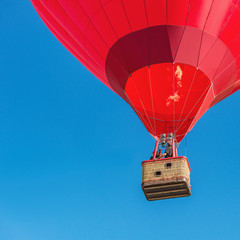 Red hot air balloon on blue sky background.