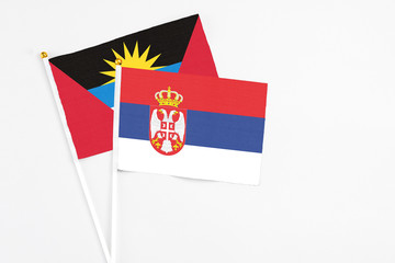 Serbia and Antigua and Barbuda stick flags on white background. High quality fabric, miniature national flag. Peaceful global concept.White floor for copy space.