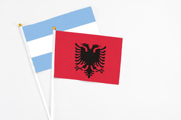 Albania and Argentina stick flags on white background. High quality fabric, miniature national flag. Peaceful global concept.White floor for copy space.