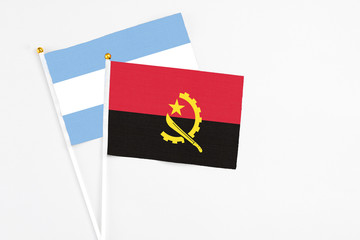 Angola and Argentina stick flags on white background. High quality fabric, miniature national flag. Peaceful global concept.White floor for copy space.