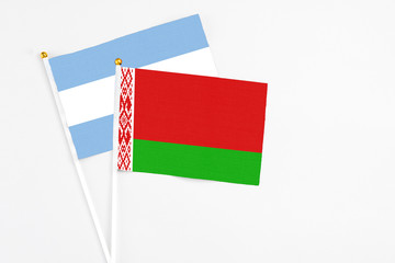 Belarus and Argentina stick flags on white background. High quality fabric, miniature national flag. Peaceful global concept.White floor for copy space.