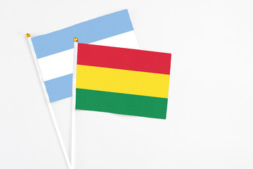 Bolivia and Argentina stick flags on white background. High quality fabric, miniature national flag. Peaceful global concept.White floor for copy space.