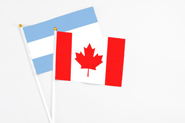 Canada and Argentina stick flags on white background. High quality fabric, miniature national flag. Peaceful global concept.White floor for copy space.