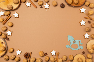 Weihnachtlicher, brauner Hintergrund mit Walnüssen, Zimtsternen und Baumscheiben, mit Textfreiraum 