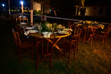Fototapeta na wymiar tables and chairs in restaurant, outdoor tables at night, tables set in the garden at an evening event