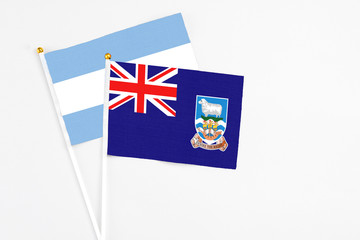 Falkland Islands and Argentina stick flags on white background. High quality fabric, miniature national flag. Peaceful global concept.White floor for copy space.