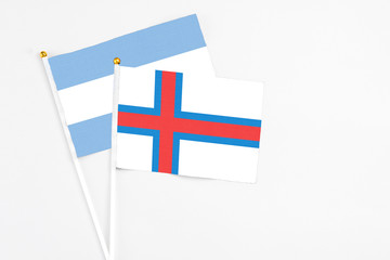 Obraz premium Faroe Islands and Argentina stick flags on white background. High quality fabric, miniature national flag. Peaceful global concept.White floor for copy space.