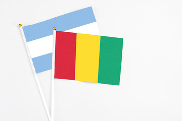 Guinea and Argentina stick flags on white background. High quality fabric, miniature national flag. Peaceful global concept.White floor for copy space.