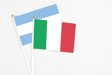 Italy and Argentina stick flags on white background. High quality fabric, miniature national flag. Peaceful global concept.White floor for copy space.