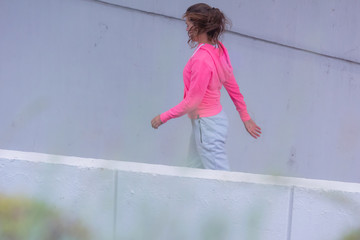 Young female runner in hoody jogging in the city street.Fit body requires hard work. Urban sport concept. Young female exercising in sport clothes.
