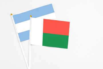 Madagascar and Argentina stick flags on white background. High quality fabric, miniature national flag. Peaceful global concept.White floor for copy space.