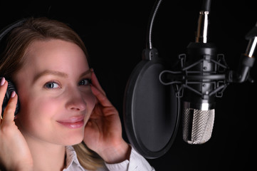 Female vocal recording. Young girl with microphone and headphones in recording studio. Recording of...
