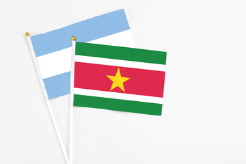 Suriname and Argentina stick flags on white background. High quality fabric, miniature national flag. Peaceful global concept.White floor for copy space.