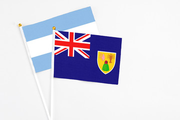 Fototapeta premium Turks And Caicos Islands and Argentina stick flags on white background. High quality fabric, miniature national flag. Peaceful global concept.White floor for copy space.