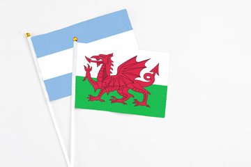 Wales and Argentina stick flags on white background. High quality fabric, miniature national flag. Peaceful global concept.White floor for copy space.