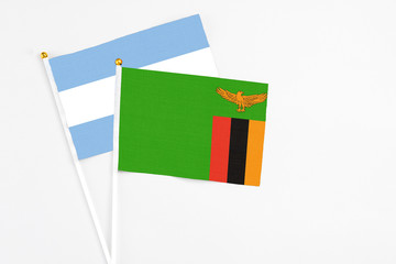 Zambia and Argentina stick flags on white background. High quality fabric, miniature national flag. Peaceful global concept.White floor for copy space.