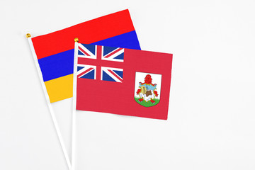 Bermuda and Armenia stick flags on white background. High quality fabric, miniature national flag. Peaceful global concept.White floor for copy space.