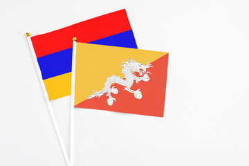 Bhutan and Armenia stick flags on white background. High quality fabric, miniature national flag. Peaceful global concept.White floor for copy space.
