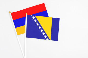 Bosnia Herzegovina and Armenia stick flags on white background. High quality fabric, miniature national flag. Peaceful global concept.White floor for copy space.