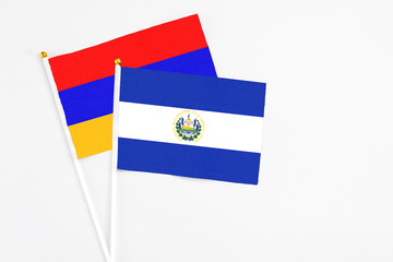El Salvador and Armenia stick flags on white background. High quality fabric, miniature national flag. Peaceful global concept.White floor for copy space.