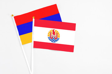 French Polynesia and Armenia stick flags on white background. High quality fabric, miniature national flag. Peaceful global concept.White floor for copy space.