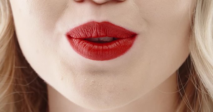 Close up shot of face of girl wearing bright red lipstick seductively biting lips and blowing kisses 4k footage