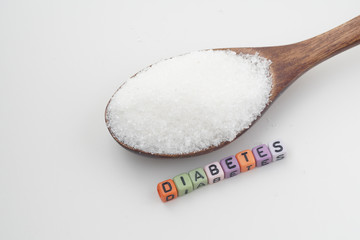 Health concept. Sugar in a wooden spoon with a DIABETES wording