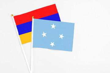 Micronesia and Armenia stick flags on white background. High quality fabric, miniature national flag. Peaceful global concept.White floor for copy space.