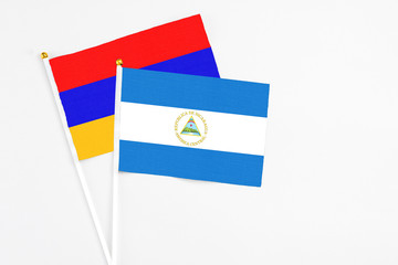 Nicaragua and Armenia stick flags on white background. High quality fabric, miniature national flag. Peaceful global concept.White floor for copy space.