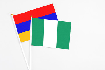 Nigeria and Armenia stick flags on white background. High quality fabric, miniature national flag. Peaceful global concept.White floor for copy space.
